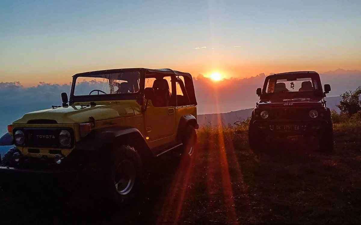 A four-wheel-drive jeep parked on the rim of Mount Batur at sunrise