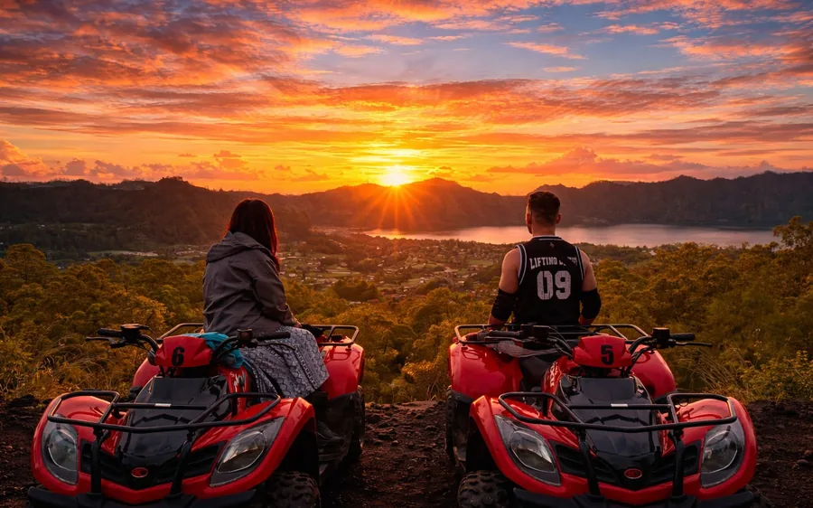 Two riders on red quad bikes looking out at a sunrise over the lake