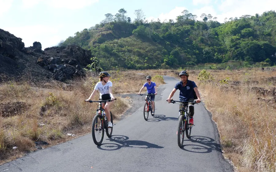 Three cyclists on a road running along the edge of a black lava field